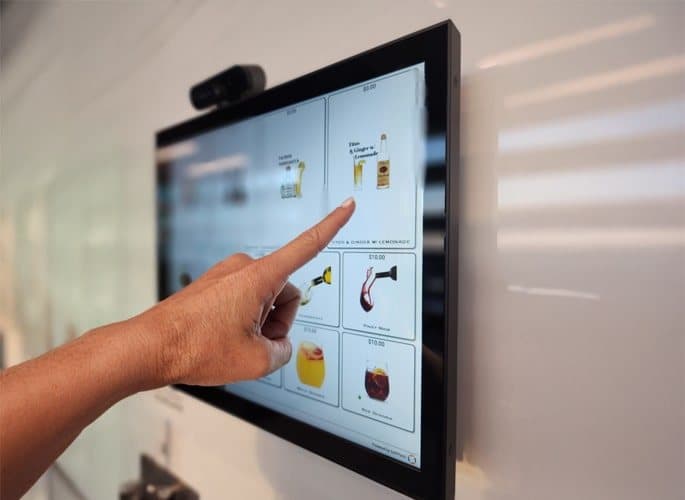 A customer ordering on a wall-mounted self-service kiosk