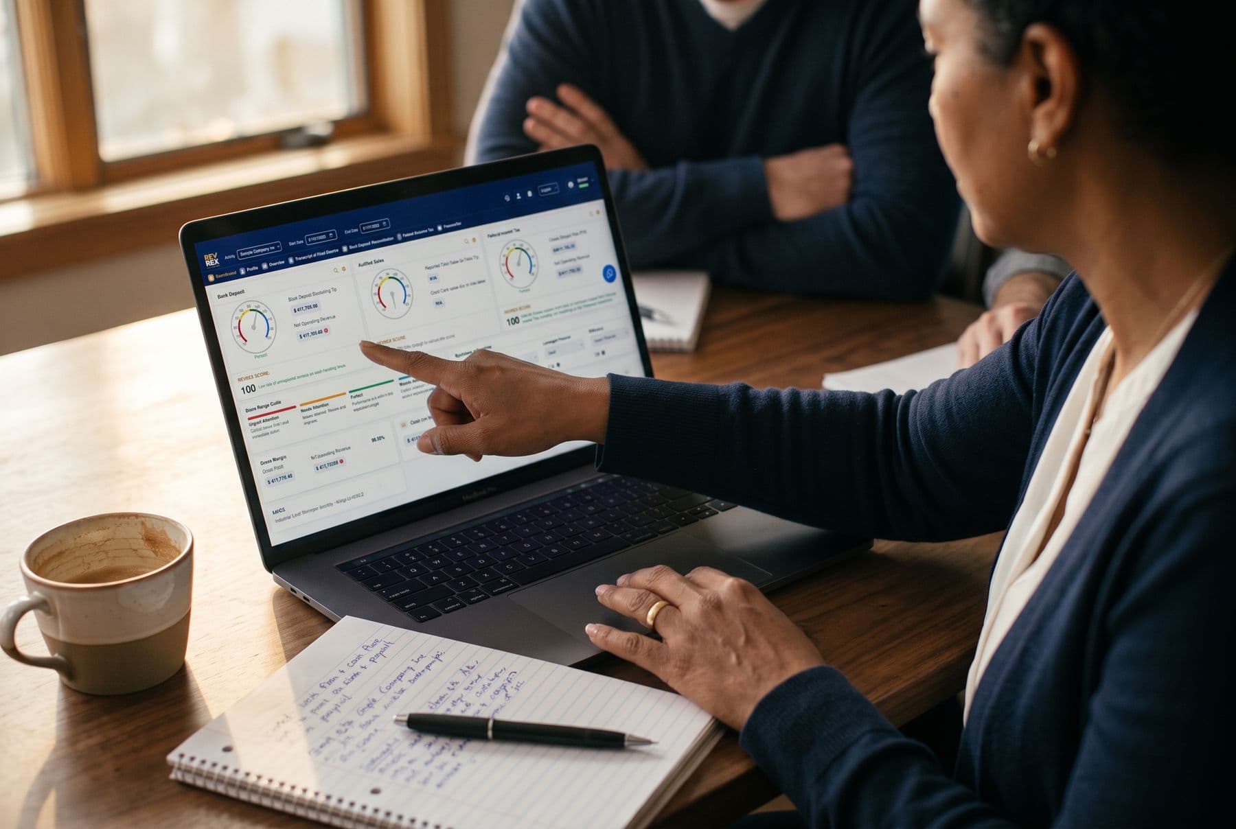 A business owner pointing at the REVREX Financial Scorecard on a laptop